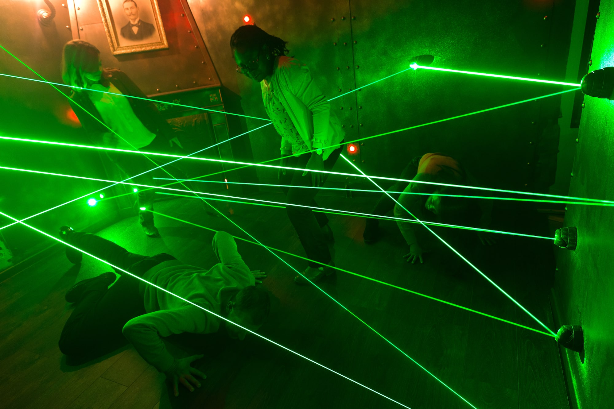 4 personnes essayant de passer des lasers verts sans les toucher